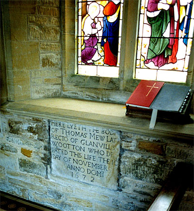 This monument reset in the south wall of the chancel to Thomas Mew, 1672, rector. It is a plain stone slab with bold Roman lettering.