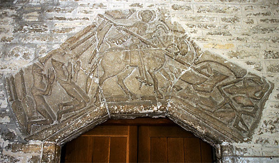 The Tympanum over the door is of great antiquity, and may have been given to the church by William Belet, who was rewarded with the manor of Fordington by William the Conqueror. It is recorded that Belet went on the first Crusade. It would seem he was being hard pressed by the Saracens at the Battle of Dorylaeum 1097, when St. George came to his aid. He and his Squire have fallen to their knees in thankfulness. There are some small differences in the armour of the two groups.