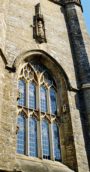 Over the entrance to St. Marfy's church the large four light west tower window and above that a statue of the Virgin Mary: it is one of the few not to have been destroyed by Cromwell's men.